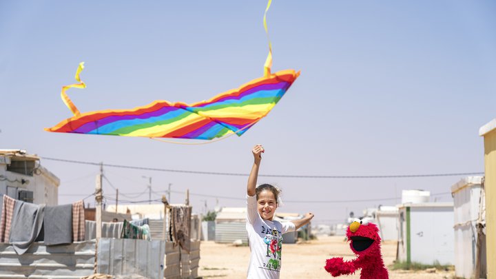 A friend shows Elmo how to fly a kite at Azraq Camp, Jordan.