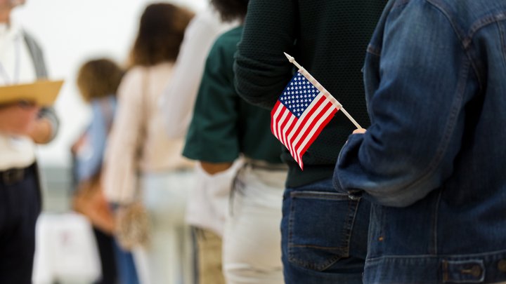 A person holds a small American flag while standing in line to vote