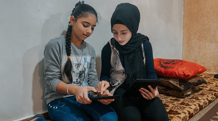 Cousins Majed (right) and Majida (left) study on their iPads provided by the Basmeh & Zeitooneh Education Program at Shatila Camp, Beirut after switching from face-to-face learning activities to online amid the COVID-19 pandemic.