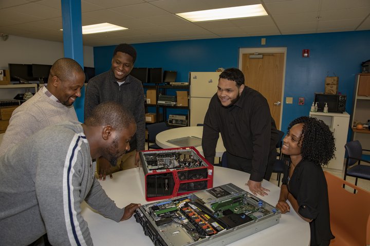 A group of Per Scholas students taking apart of computer in class